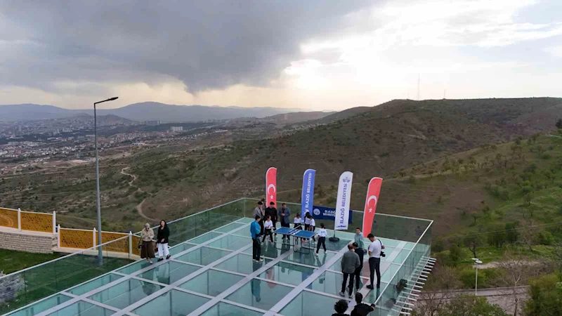 Cam teras üzerinde masa tenisi karşılaşması, renkli görüntüler oluşturdu
